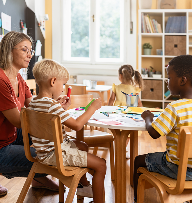 Ein paar Kinder sitzen um einen Tisch und Basteln