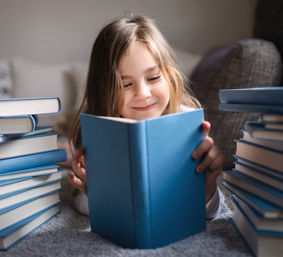 Mädchen schaut in ein blaues Buch und lächelt