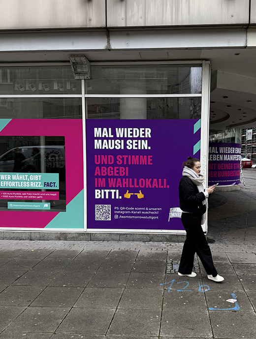 Frau vor lila Plakat das an einer Fensterscheibe klebt