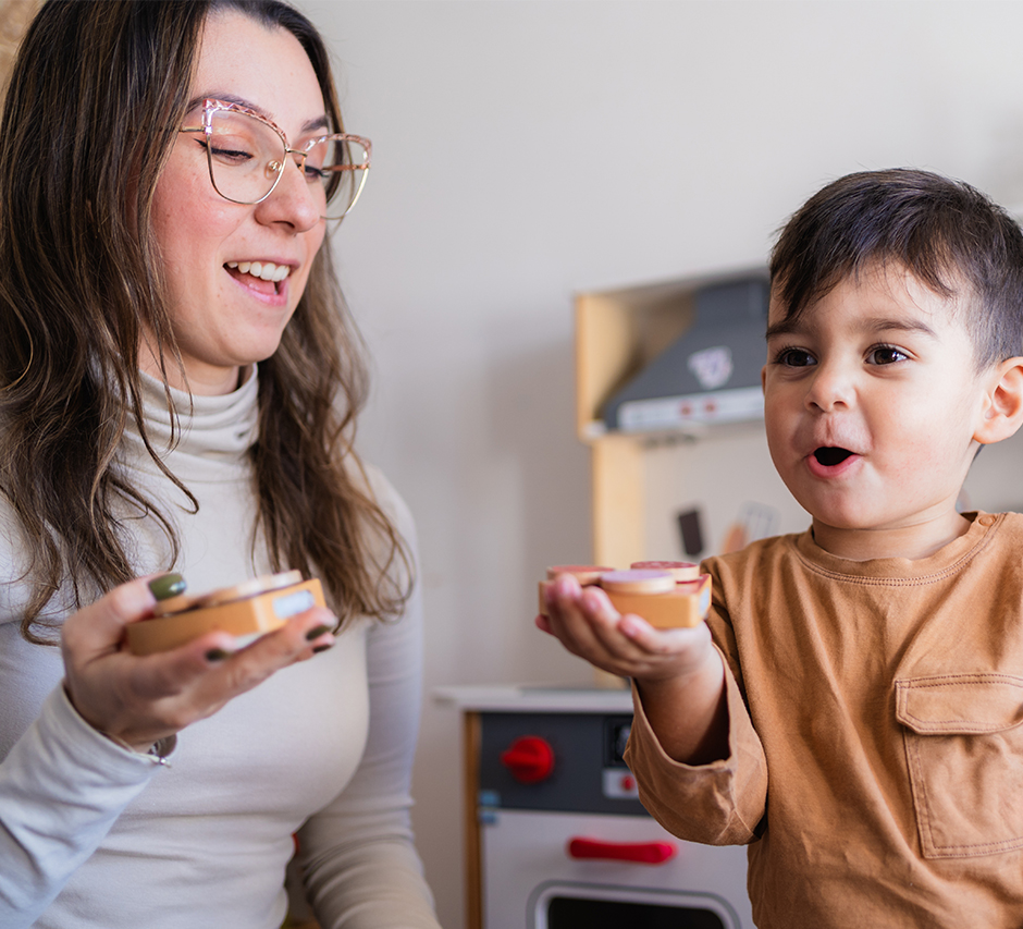 Kleiner Junge mit Spielzeug freut sich neben sein Mutter