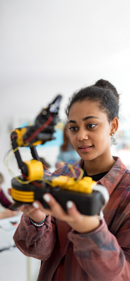 Junges Mädchen hält einen schwarz-gelben Roboter in der Hand