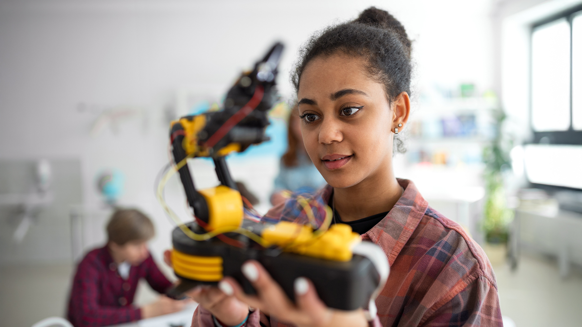 Junges Mädchen hält einen schwarz-gelben Roboter in der Hand