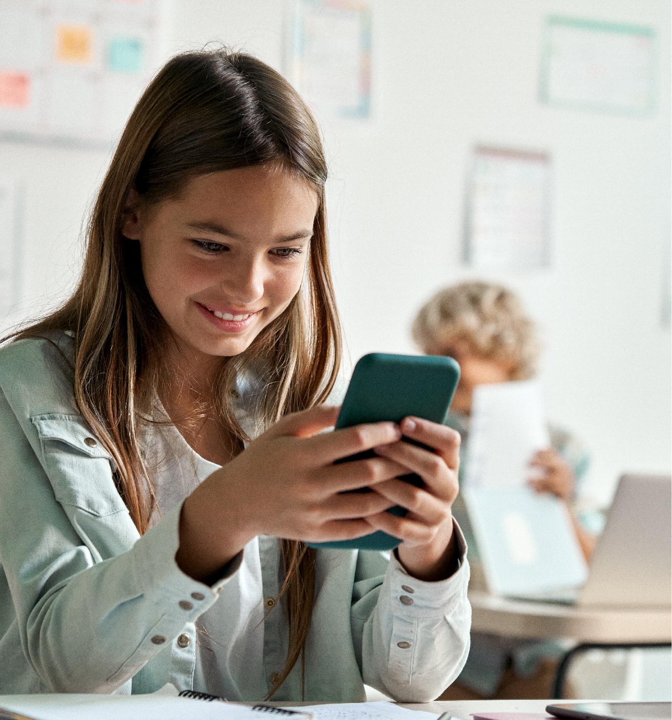 Young girl looks into a mobile phone with a smile.