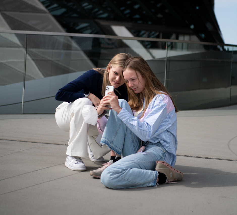 Zwei Teenagerinnen sehen auf ein Smartphone