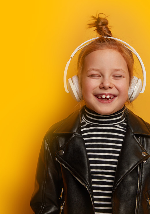 Girl on yellow background smiling with headphones listening to an audio book.