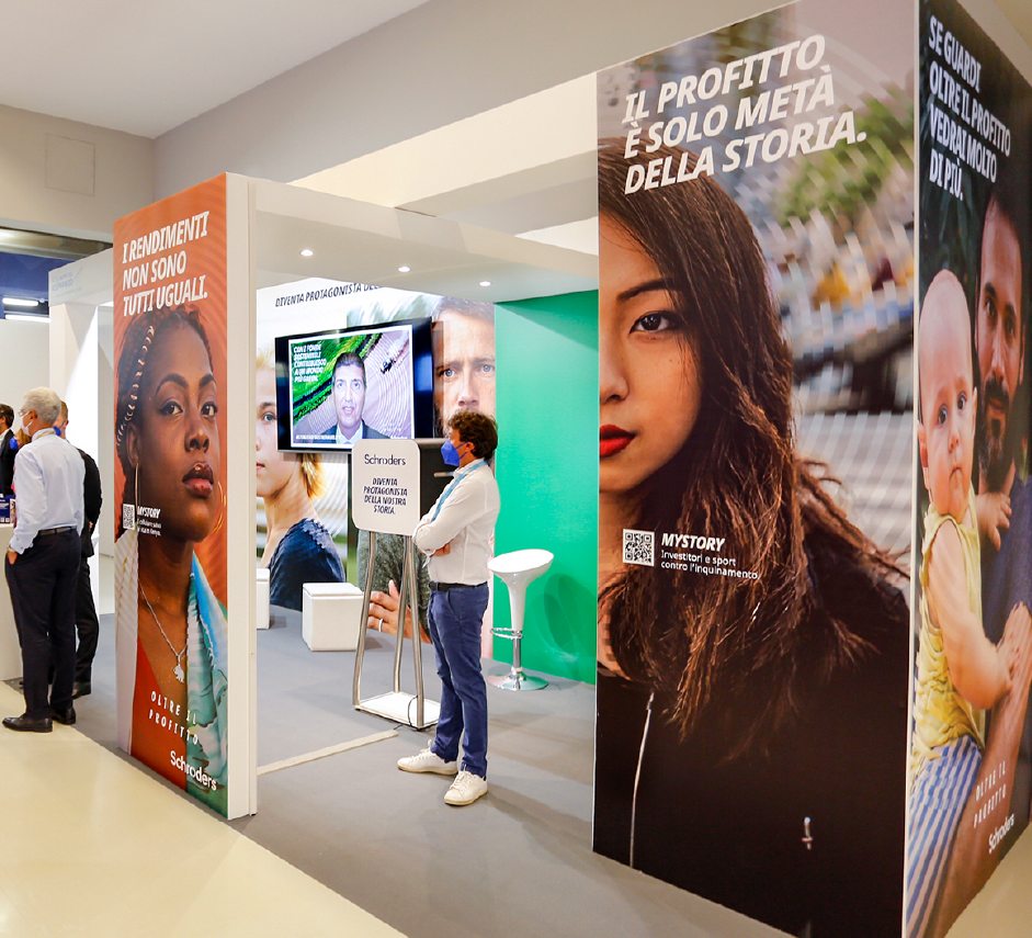 Stand fieristici con testi come "Il profitto è solo metà della storia" e "I rendimenti non sono tutti uguali". Visitatori esplorano investimenti sostenibili con Schroders.