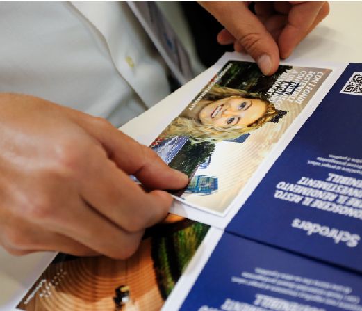 «Con i fondi sostenibili contribuisco a un mondo più sano» è scritto su un’immagine tenuta da una mano, accanto a un opuscolo blu con il logo Schroders.