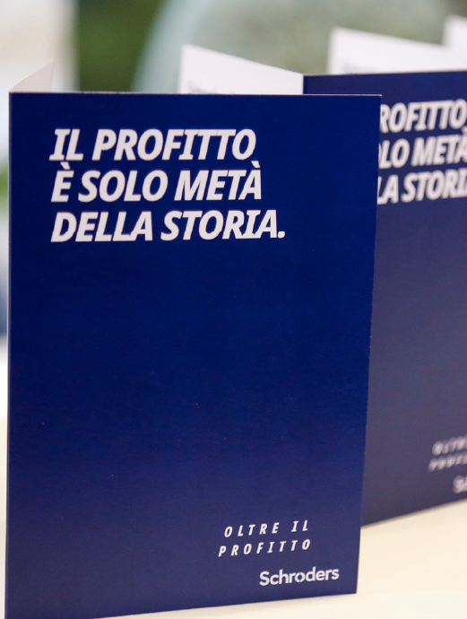 "Il profitto è solo metà della storia." scritto su opuscoli blu con il logo Schroders e il messaggio "Oltre il profitto".