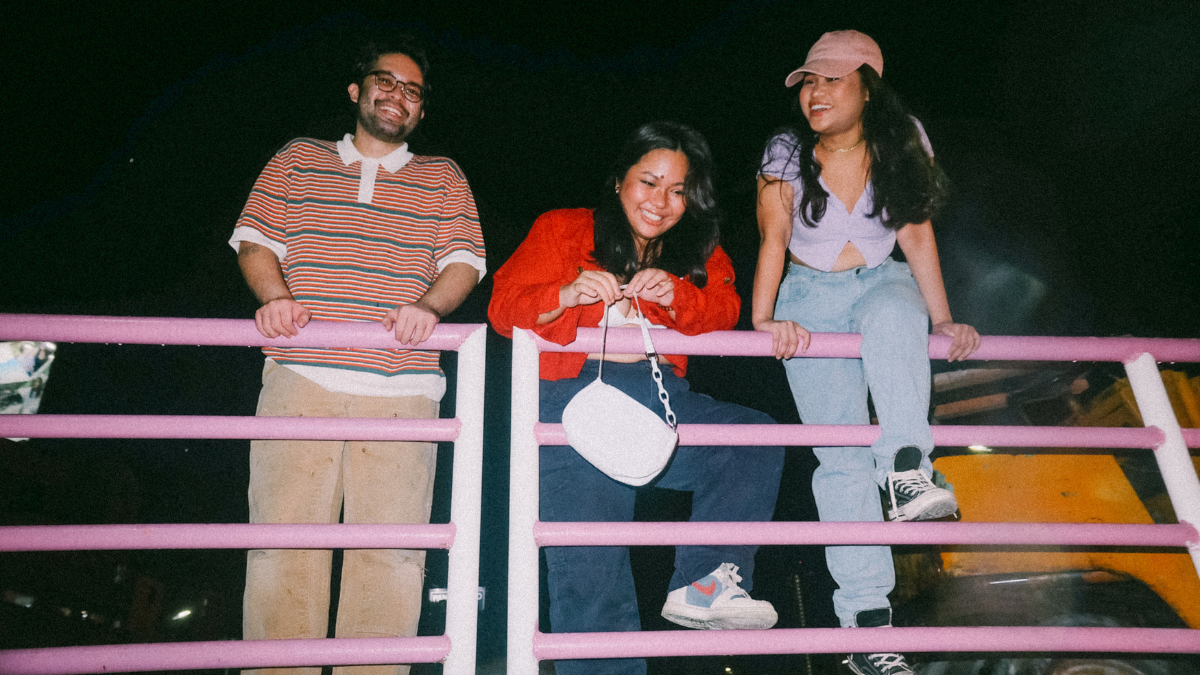 3 Teenagers leaning against a rail smiling