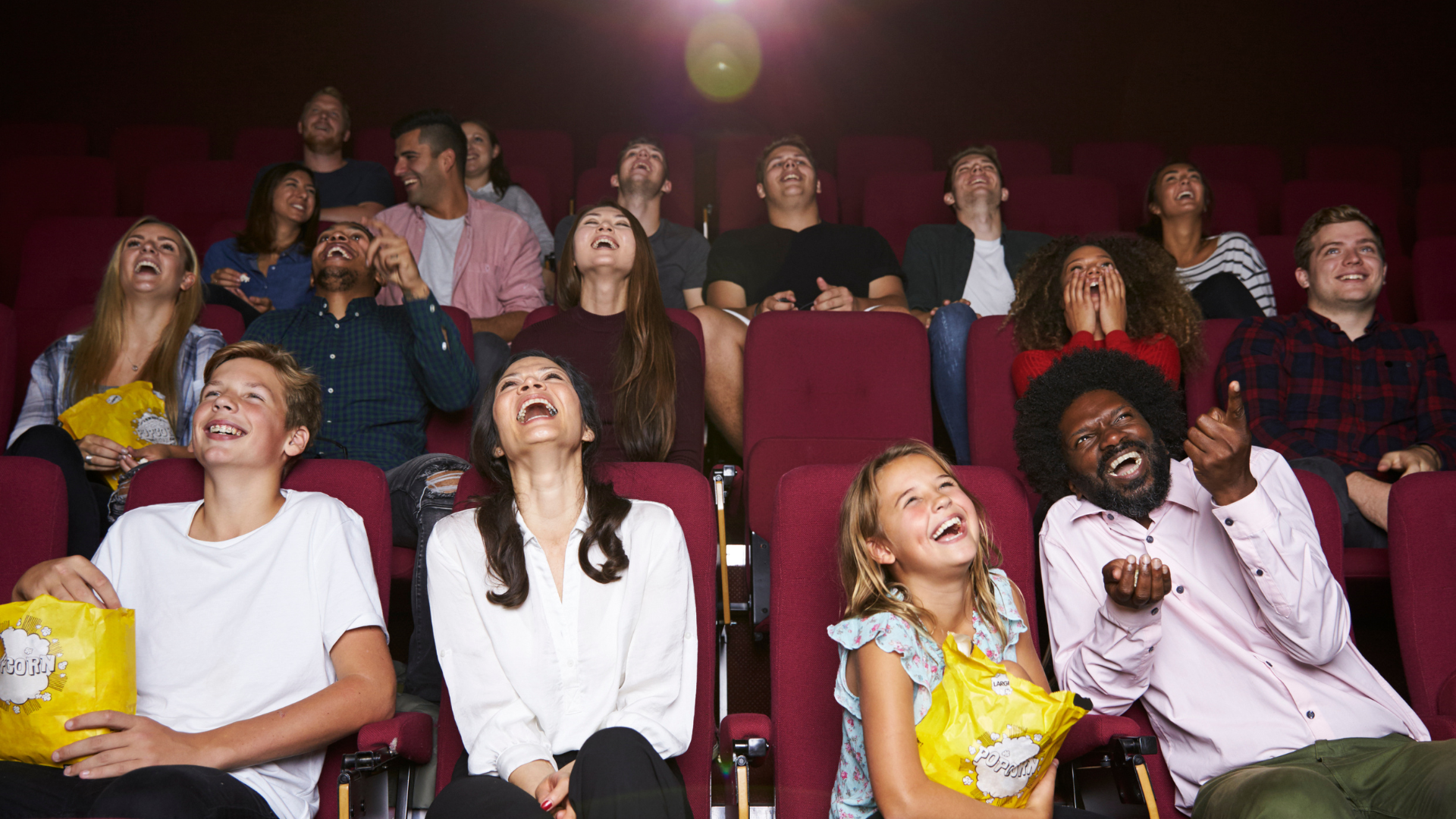 Excerpt from a movie hall with people sitting in it, all laughing and happy.