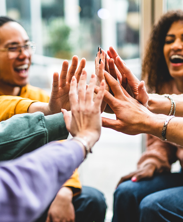 A group of friends joyfully brings their hands together in a high-five, symbolizing unity and celebration.